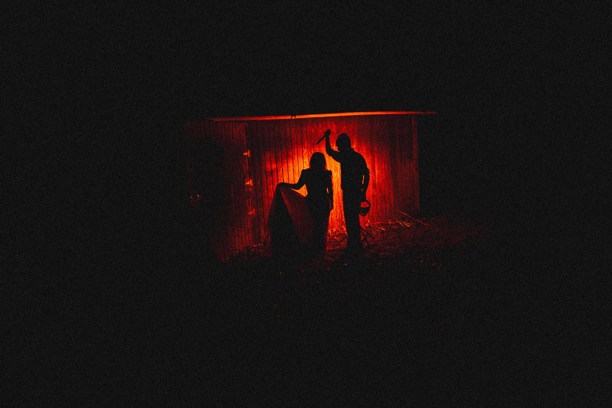 Spooky Halloween photo - silhouette of woman in wedding dress with man holding knife and glowing red light behind them