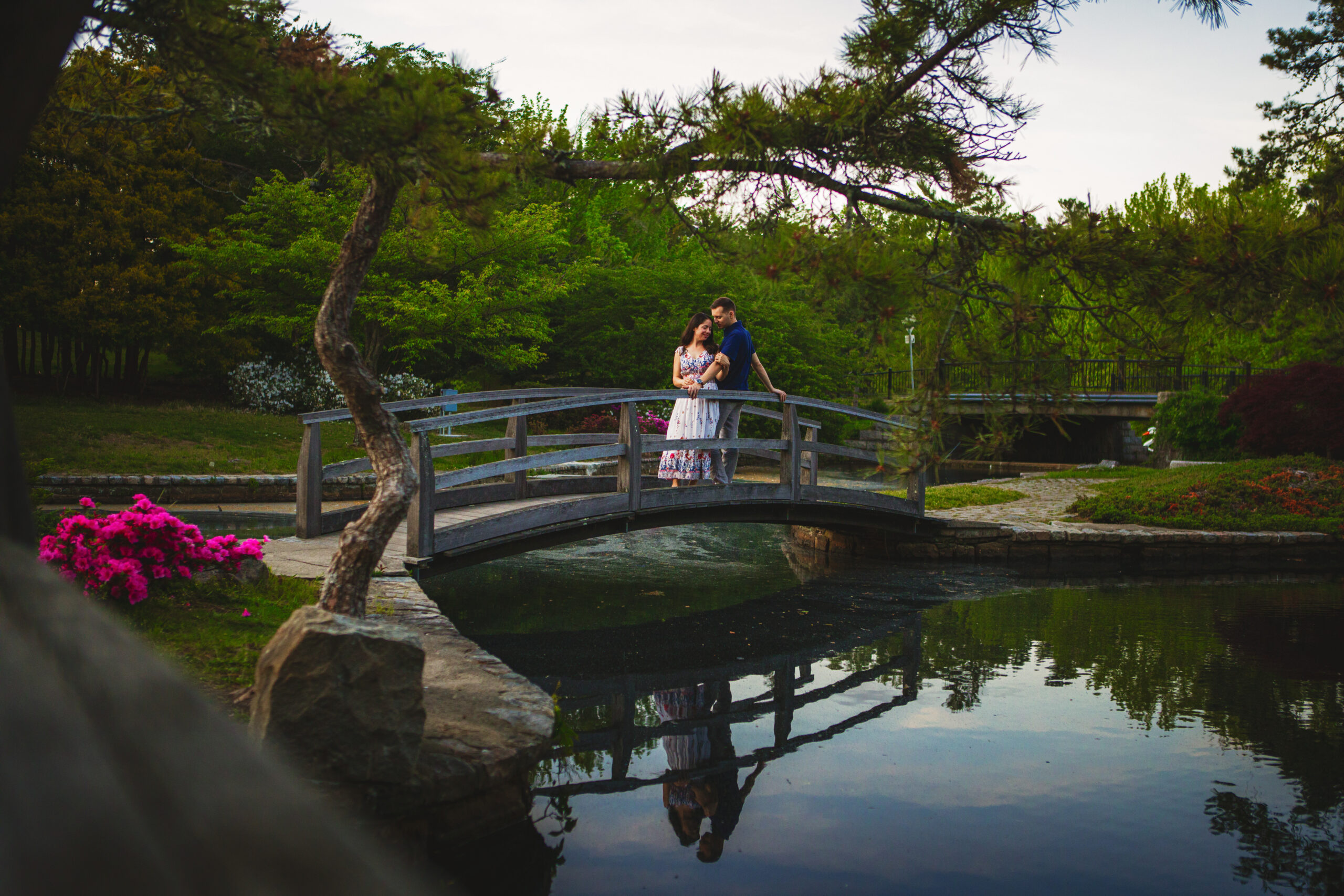 Engaged couple posing together on bridge at Roger Williams Park Zoo in Providence, RI for photoshoot